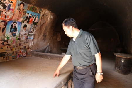 中华思源工程扶贫基金会工作人员实地考察朱家坪村残贫户危旧窑洞，窑洞墙面上的贴画展现出残贫户对美好生活的憧憬
